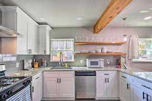 A modern kitchen with white cabinets, a stainless steel dishwasher, a microwave, and a gas stove. - San Antonio Home ~ 4 Mi to Dtwn + The Pearl! (San Antonio)