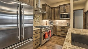 Una cocina con electrodomésticos de acero inoxidable, armarios de madera y encimera de granito.