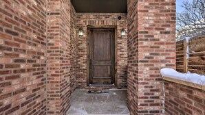 A brick-walled entrance with a wooden door, a welcome mat, and two wall-mounted lights. - 1/2 Mi to Dtwn: Golden Gem w/ Patios! (Golden)