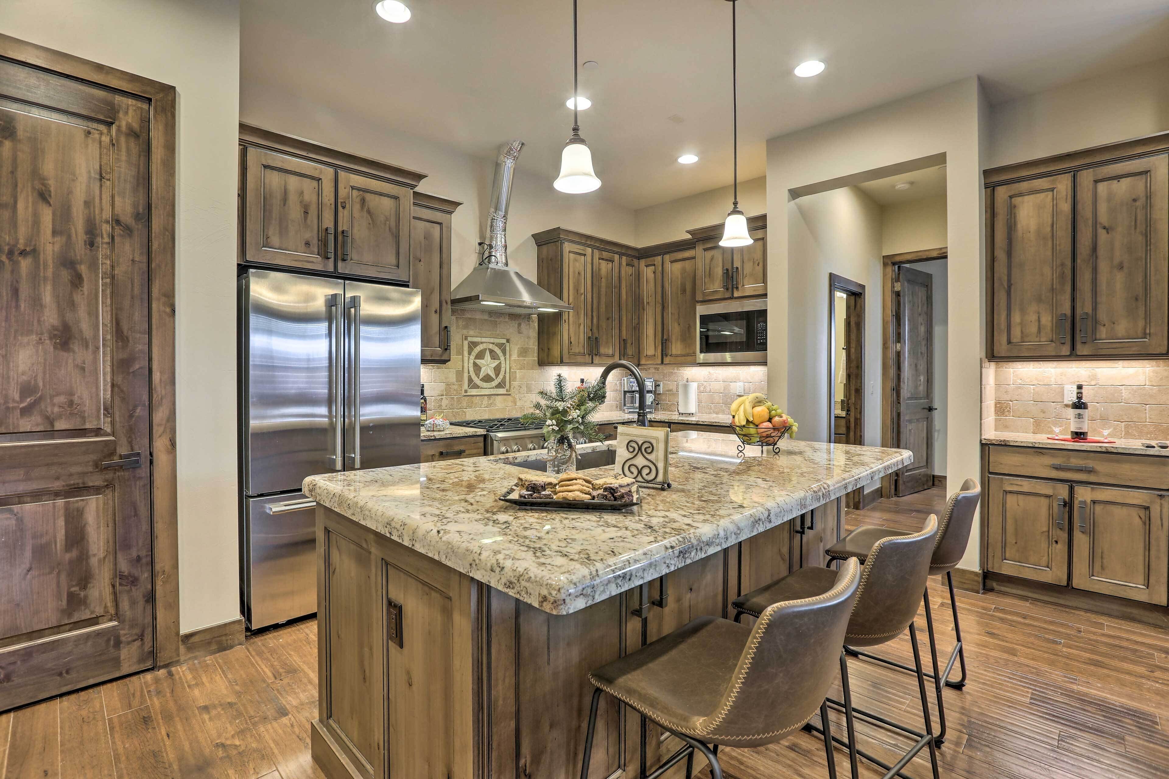 A kitchen with wooden cabinets, stainless steel appliances, a granite countertop, and pendant lighting.