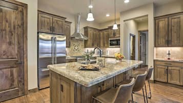 A kitchen with wooden cabinets, stainless steel appliances, a granite countertop, and pendant lighting.