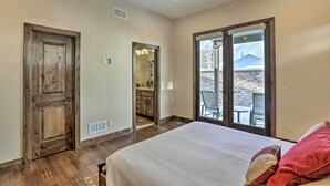 A bedroom with a large bed, wooden doors, and a view of a patio with outdoor furniture. - 1/2 Mi to Dtwn: Golden Gem w/ Patios! (Golden)