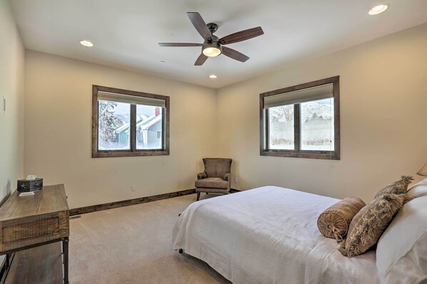 A bedroom with a bed, a chair, a desk, and two windows. - 1/2 Mi to Dtwn: Golden Gem w/ Patios! (Golden)