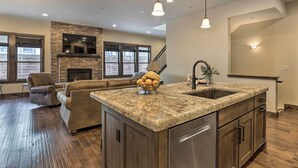 Una cocina amplia con una isla grande, armarios de madera y encimera de piedra.