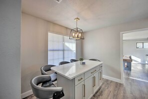 A modern kitchen with a central island, bar stools, and a pendant light.
