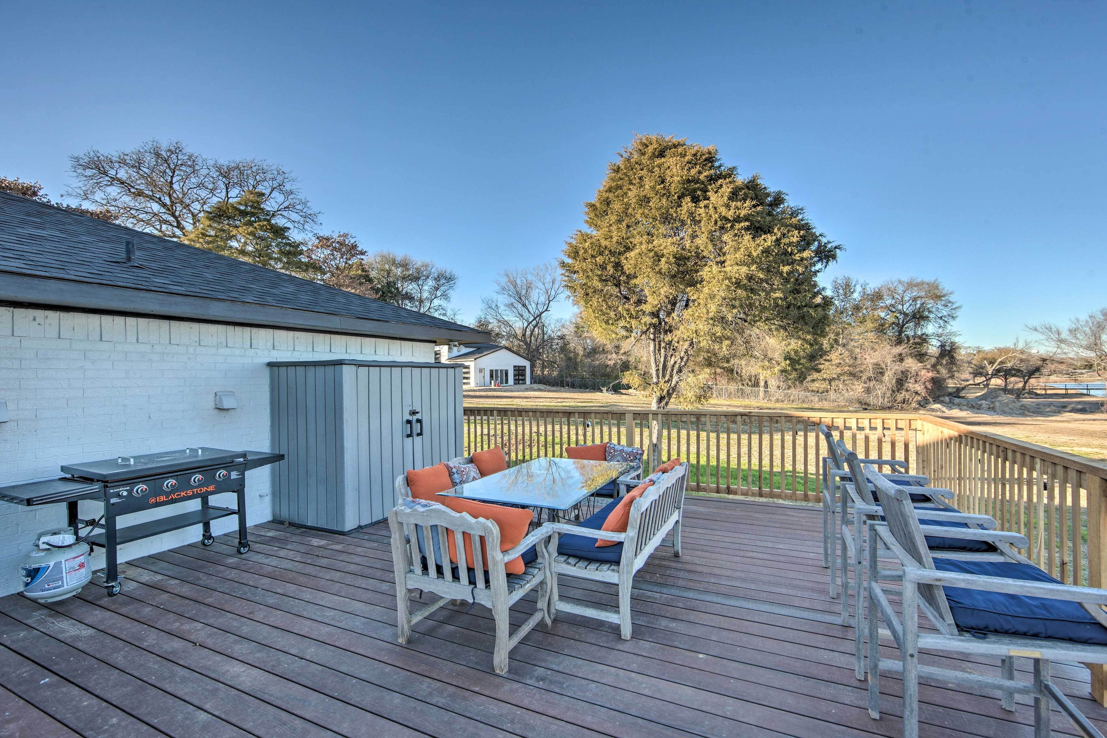 An outdoor deck with a grill, seating area, and a view of the surrounding landscape.