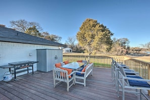 An outdoor deck with a grill, seating area, and a view of the surrounding landscape.