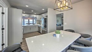 A modern kitchen with stainless steel appliances, a central island, and a dining area with chairs. - Lakefront Gun Barrel City Home w/ 5 Acres! (Mabank)