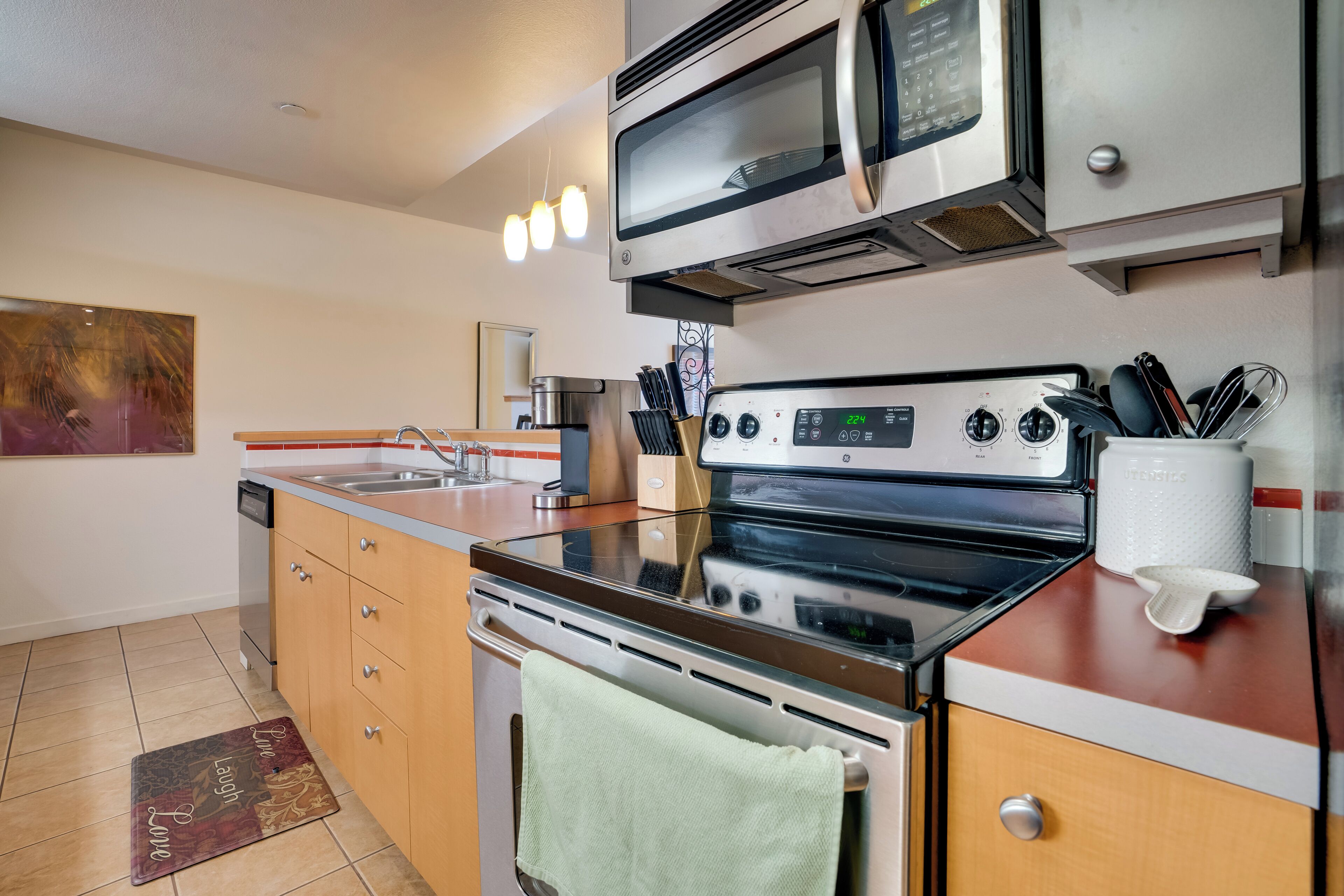 Una cocina moderna con electrodomésticos de acero inoxidable, armarios de madera y salpicadero de azulejos.