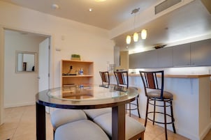 Una cocina moderna con armarios grises, una mesa redonda de vidrio y dos taburetes de bar.