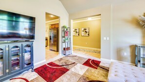 A living room with a flat-screen TV, a dark wooden cabinet, and a red and beige patterned rug.