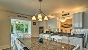 A kitchen with granite countertops, white cabinetry, and a central island with seating.