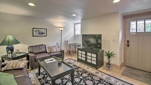 Sala de estar com sofá, mesa de centro, televisão e armário.