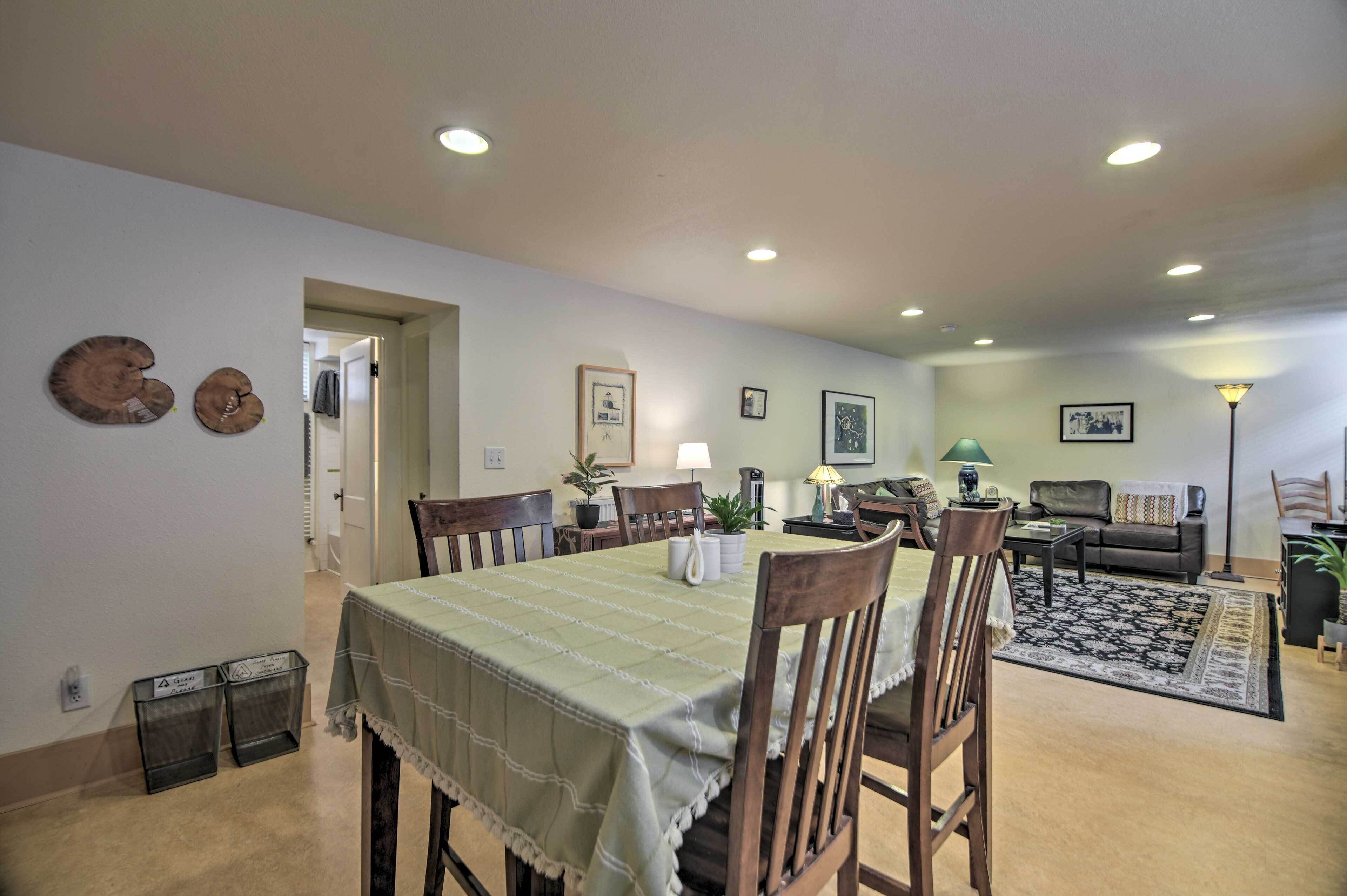 A dining area with a table set for four, surrounded by chairs, and a living room area with a sofa and a coffee table.