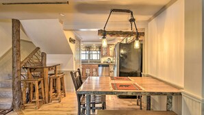 A spacious dining area with a long wooden table, chairs, and a rustic hanging light fixture. - Townhome w/ Deck: Walk to Mirror Lake & Main St! (Lake Placid)