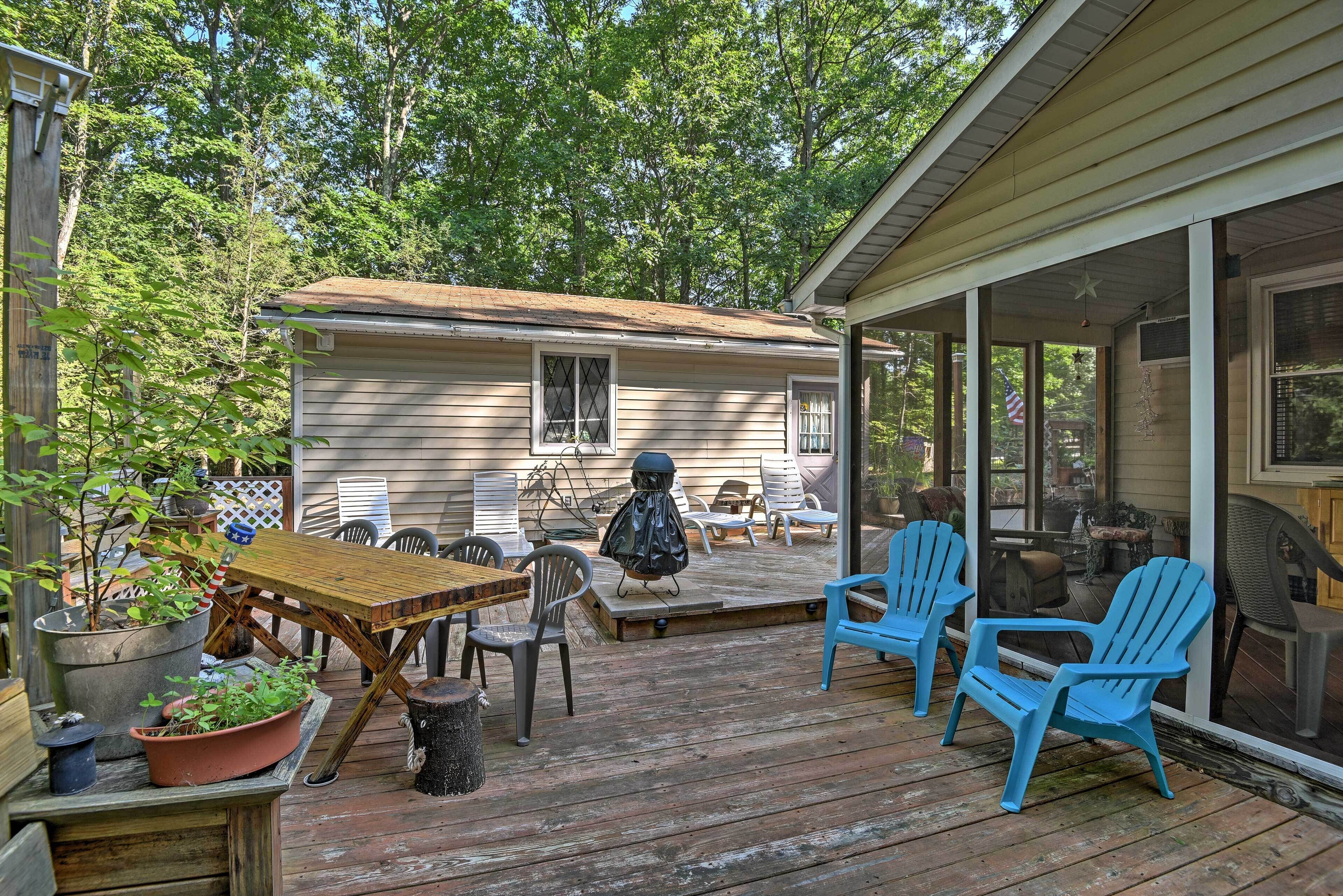 A wooden deck with outdoor furniture, a grill, and potted plants.