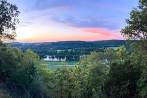 A panoramic view of a valley with a river, surrounded by dense forest and hills.