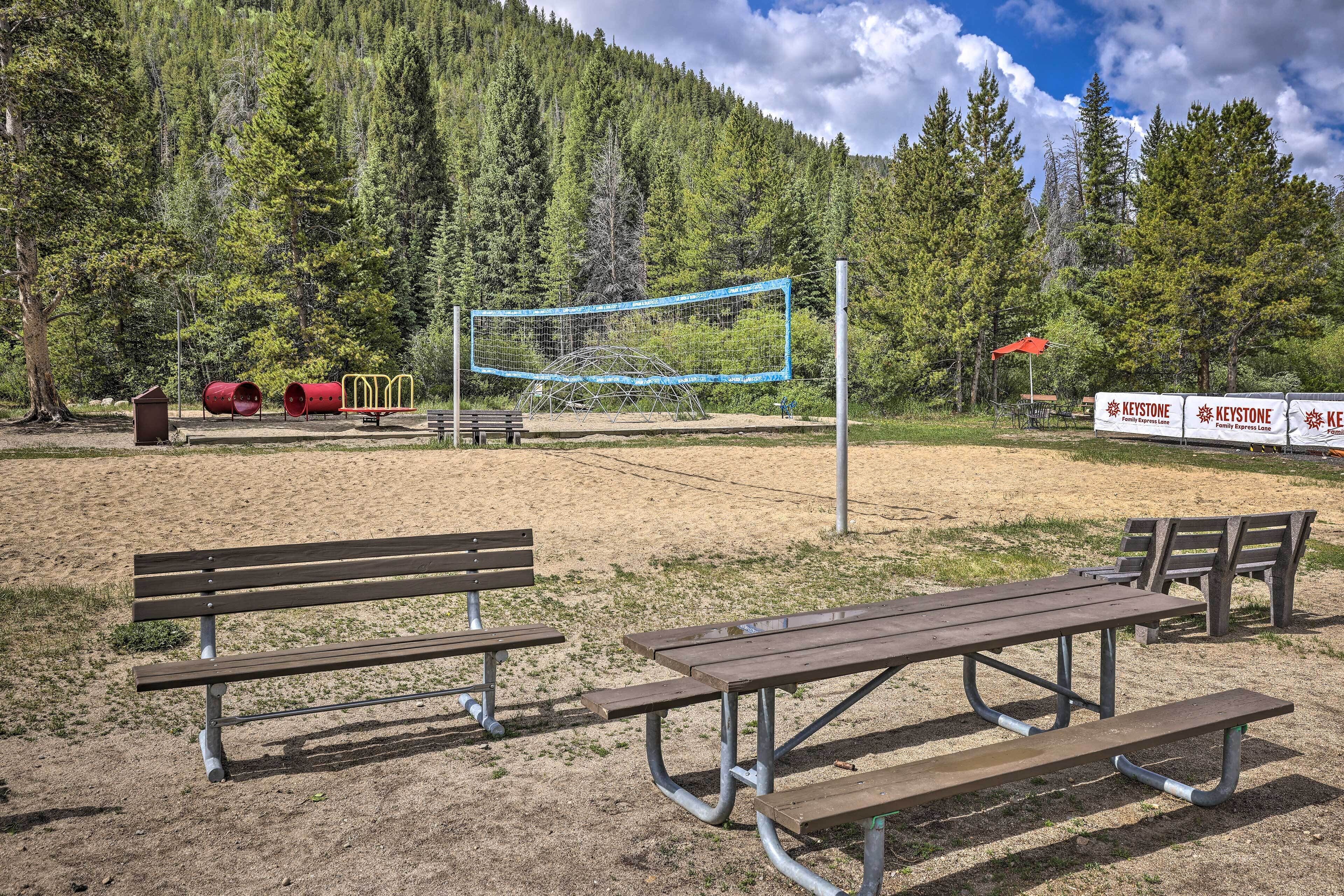 Un parc équipé de tables de pique-nique, d’un filet de volley-ball et d’aires de jeux pour enfants.