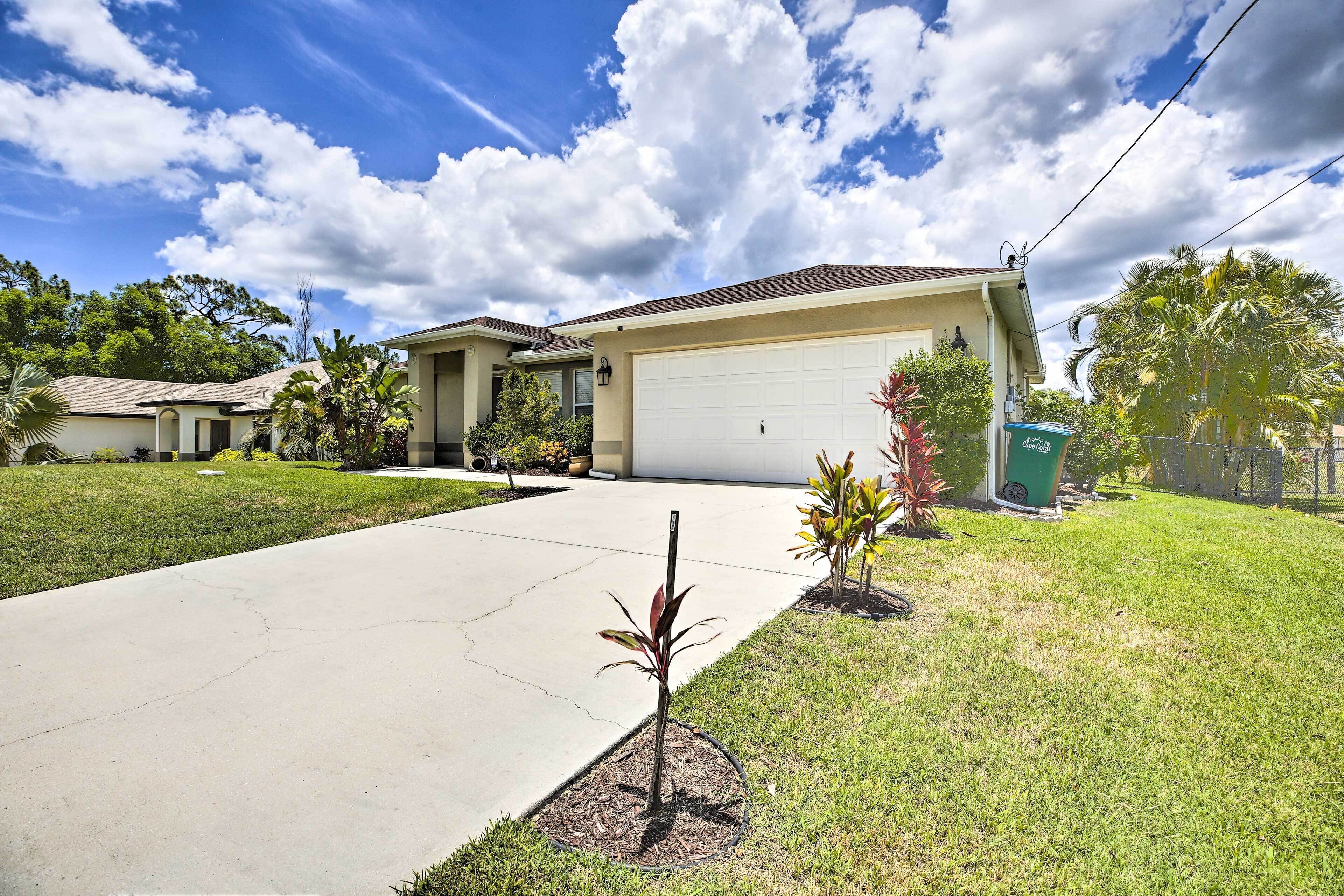 A residential house with a garage, a driveway, and a lawn with small plants.