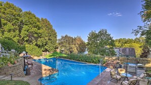 En trädgård med en pool, utemöbler och en plats för grillning.
