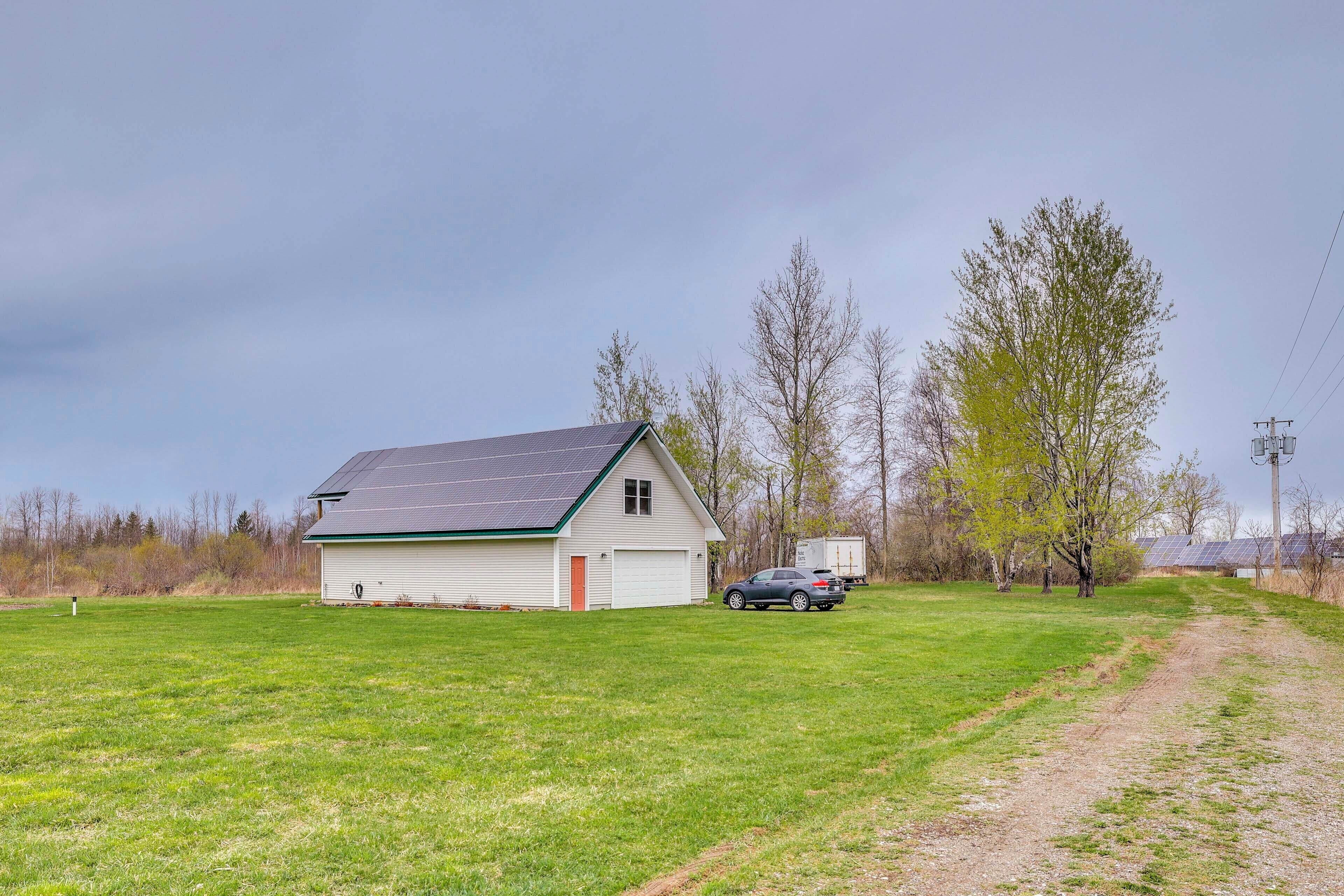 A single-story house with a garage, a car parked in front, and a dirt path leading to the house.