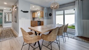 Una cocina moderna con armarios de madera, una mesa de comedor con sillas de mimbre y un amplio ventanal con cortinas.