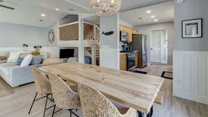 Una cocina moderna con armarios blancos, una mesa de comedor de madera y una lámpara colgante.