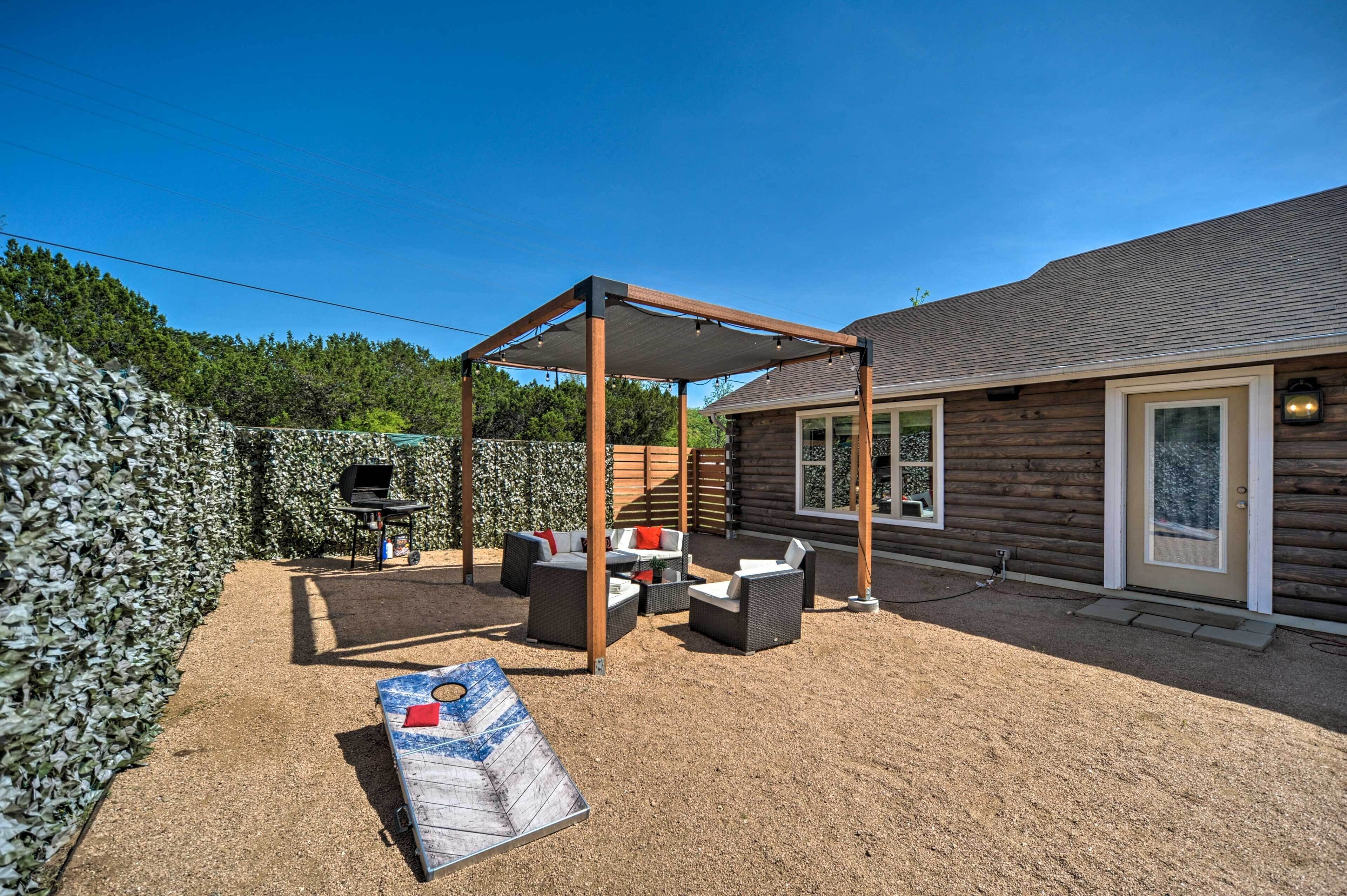 Un patio couvert aménagé avec du mobilier d’extérieur, un barbecue et un bâtiment de style cabane en bois.
