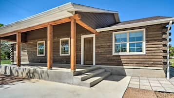 A log cabin with a covered porch, a front door, and a large window.