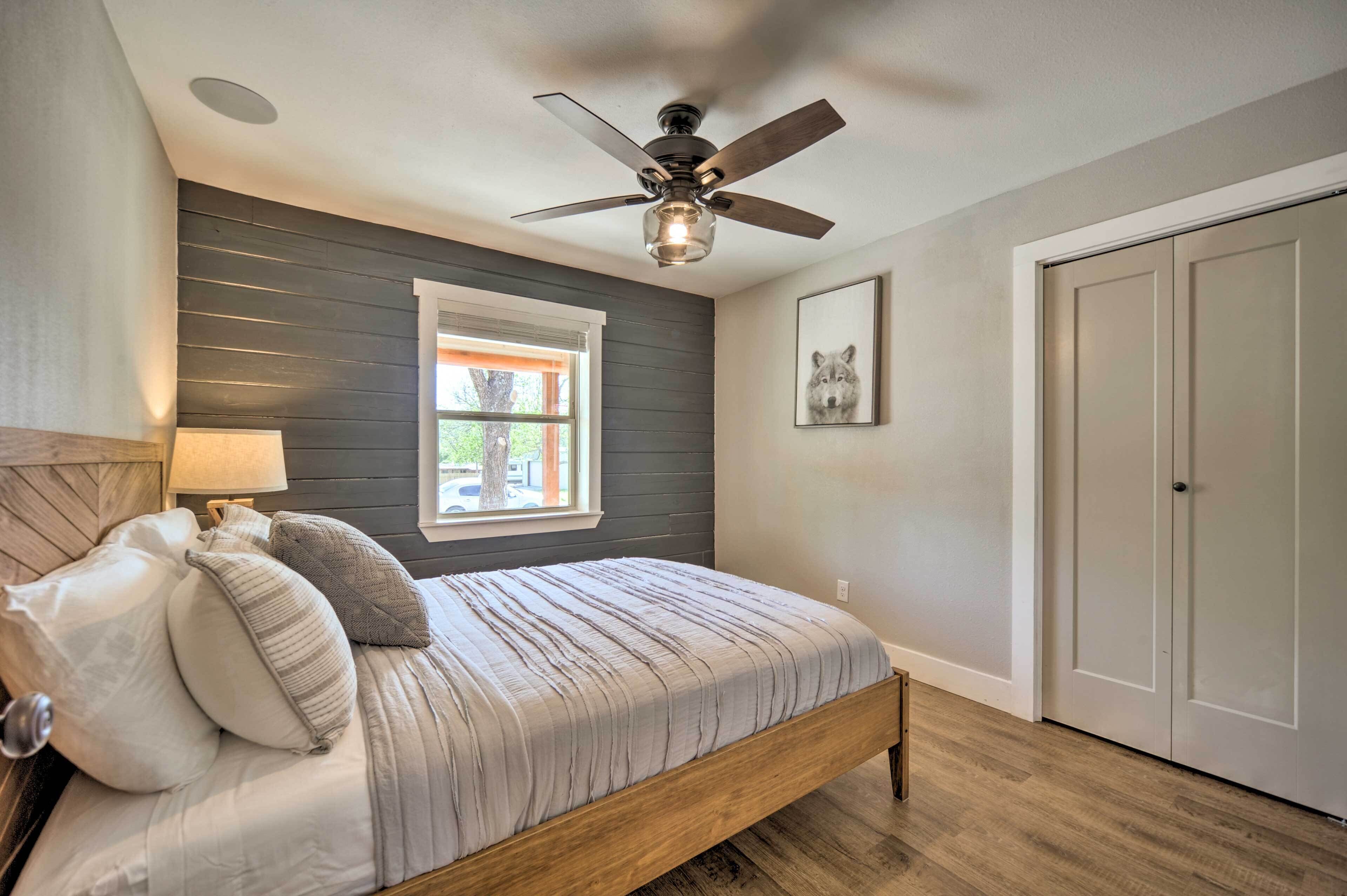 A bedroom with a bed, a ceiling fan, a window, and a door.