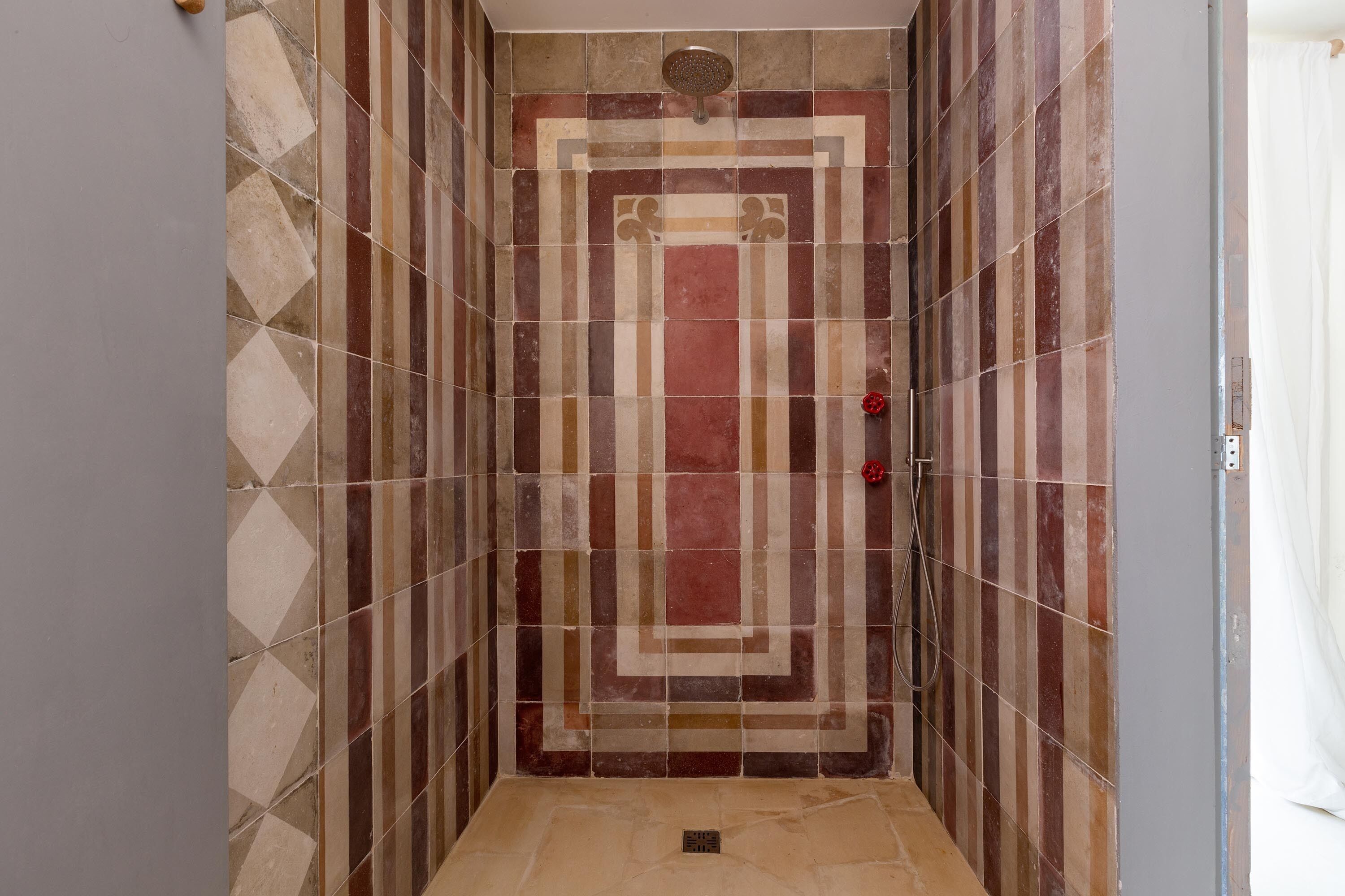 Ducha con pared de azulejos con un diseño geométrico.