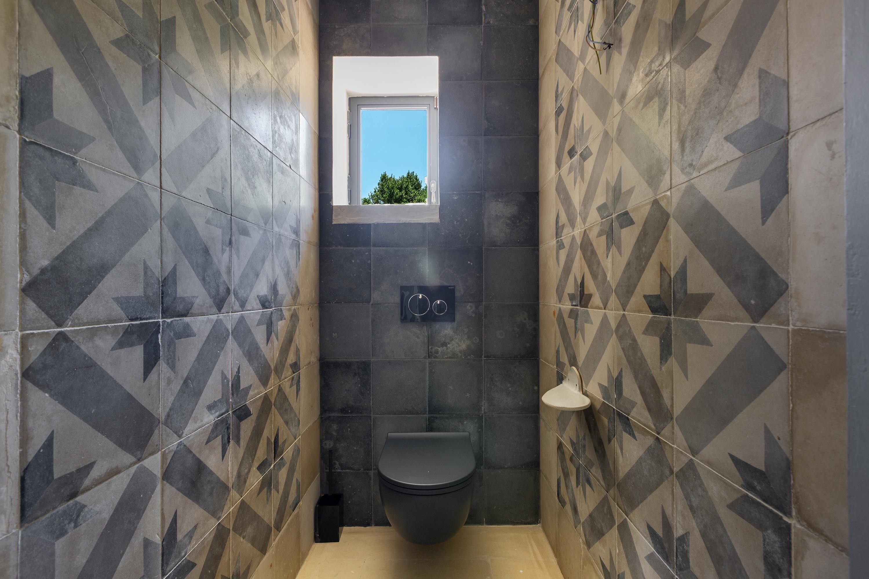 A bathroom with a black toilet, a small window, and a wall-mounted sink.