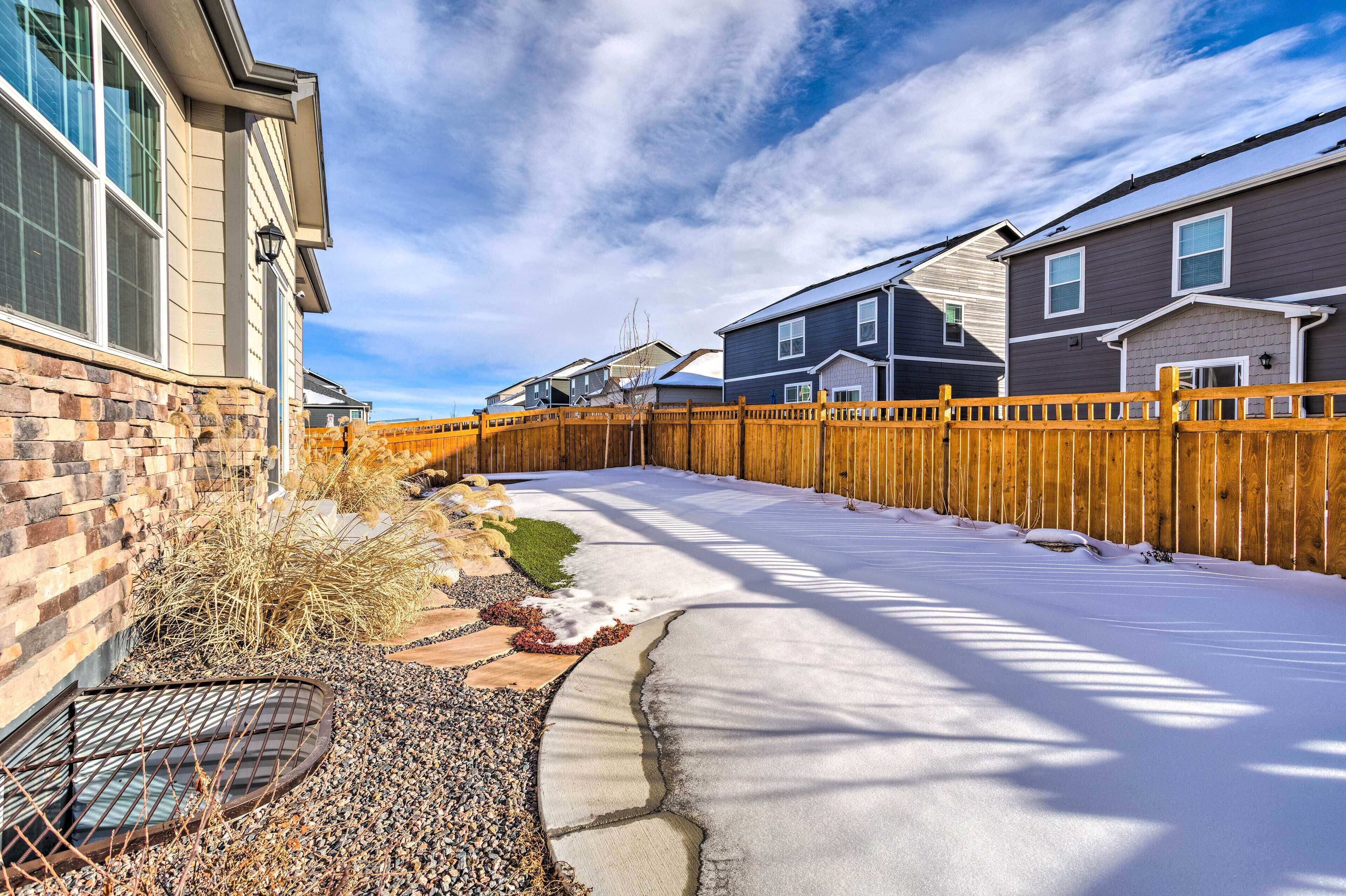 A residential area with houses, a wooden fence, and a snow-covered ground.