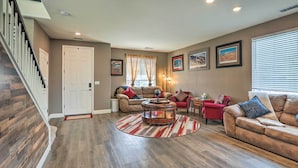 A spacious living room with a staircase, a round coffee table, and a red armchair. - Air Racing Decor, Hot Tub: Sparks Home! (Sparks)