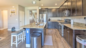 A modern kitchen with dark cabinets, stainless steel appliances, and a granite countertop. - Air Racing Decor, Hot Tub: Sparks Home! (Sparks)