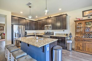A modern kitchen with dark cabinets, stainless steel appliances, a granite countertop island, and bar stools. - Air Racing Decor, Hot Tub: Sparks Home! (Sparks)