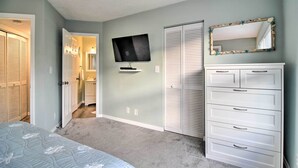 Une chambre à coucher comprenant un lit, une commode, un téléviseur et un placard.