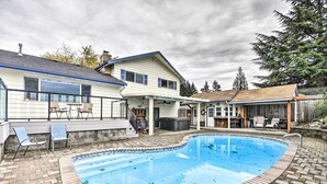 A backyard with a swimming pool, a covered patio, and a house with a blue roof. - Vancouver Home w/ Hot Tub < 15 Mi to Portland! (Vancouver)