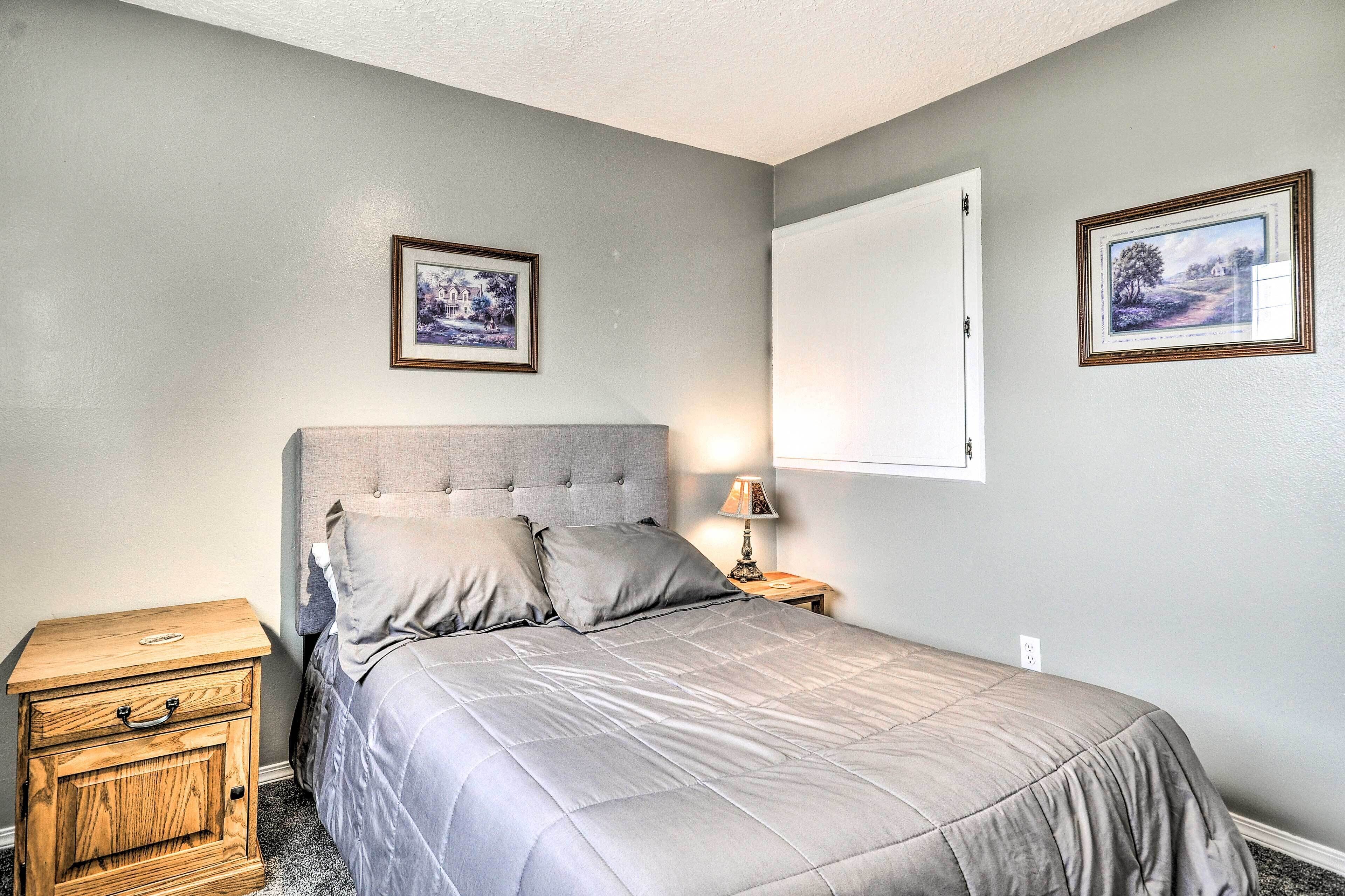 A bedroom with a bed, a nightstand, and a wall-mounted lamp.