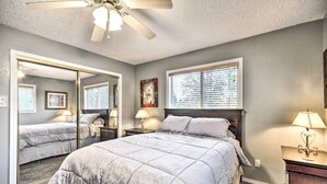 A bedroom with a large bed, a ceiling fan, a window with blinds, a nightstand with a lamp, and a dresser. - Vancouver Home w/ Hot Tub < 15 Mi to Portland! (Vancouver)