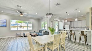A spacious living area with a dining table and chairs, a ceiling fan, and a kitchen area with bar stools. - Beautiful Getaway ~ 4 Miles to Venice Beach! (Venice)