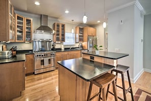 Una cocina moderna con armarios de madera, electrodomésticos de acero inoxidable y una isla central con taburetes de bar.
