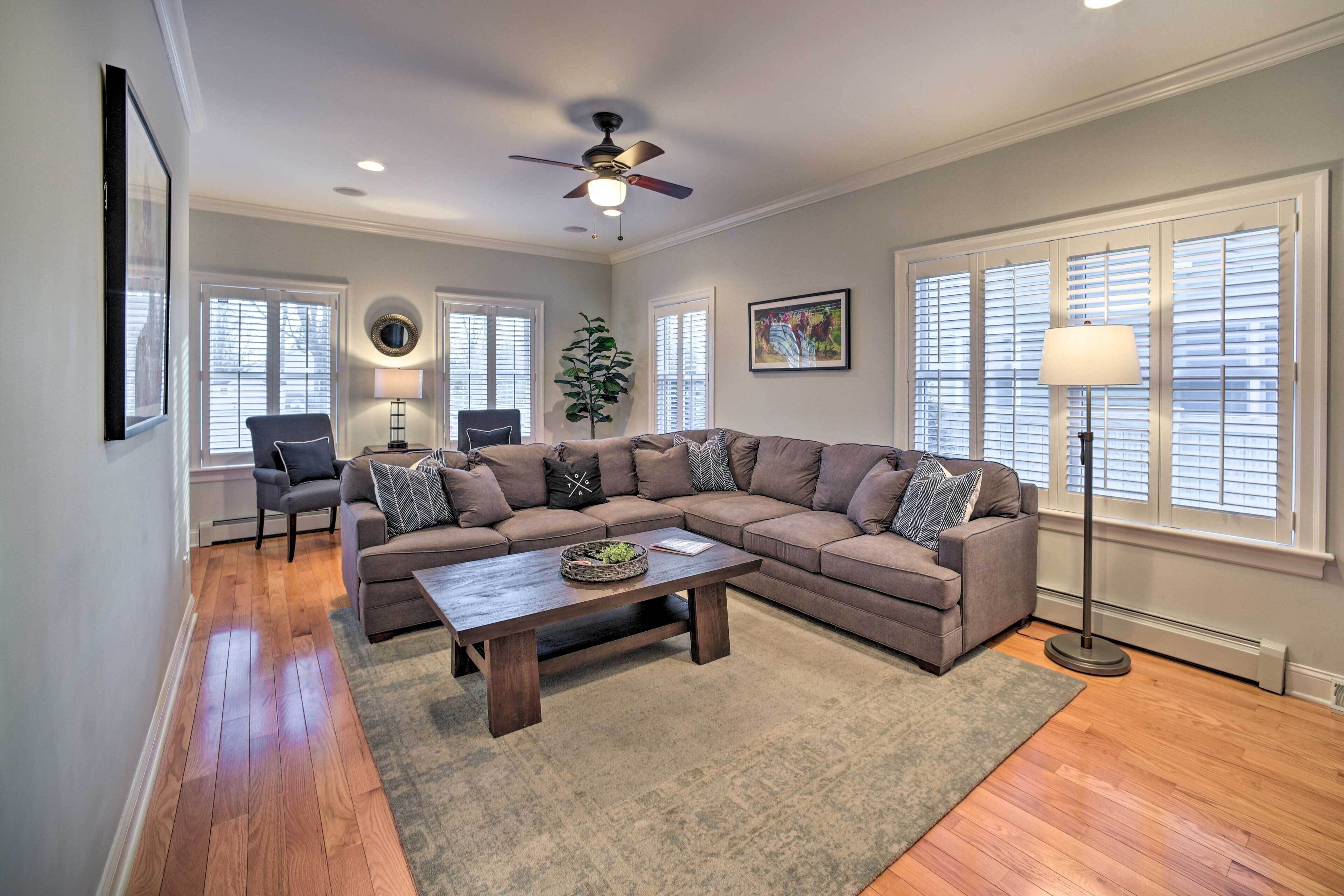 A living room with a sectional sofa, a coffee table, a floor lamp, and a ceiling fan.
