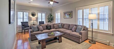 A living room with a sectional sofa, a coffee table, a floor lamp, and a ceiling fan.