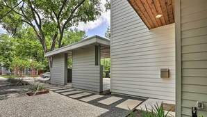 A modern house with a covered porch, a gravel driveway, and a small garden area.