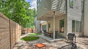 A patio area with a grill, outdoor furniture, and a wooden fence.