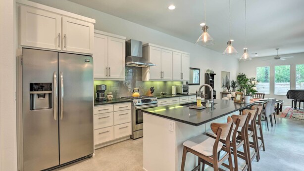 A modern kitchen with stainless steel appliances, white cabinetry, and a central island with bar stools.