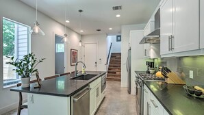 A modern kitchen with a central island, stainless steel appliances, and pendant lighting.