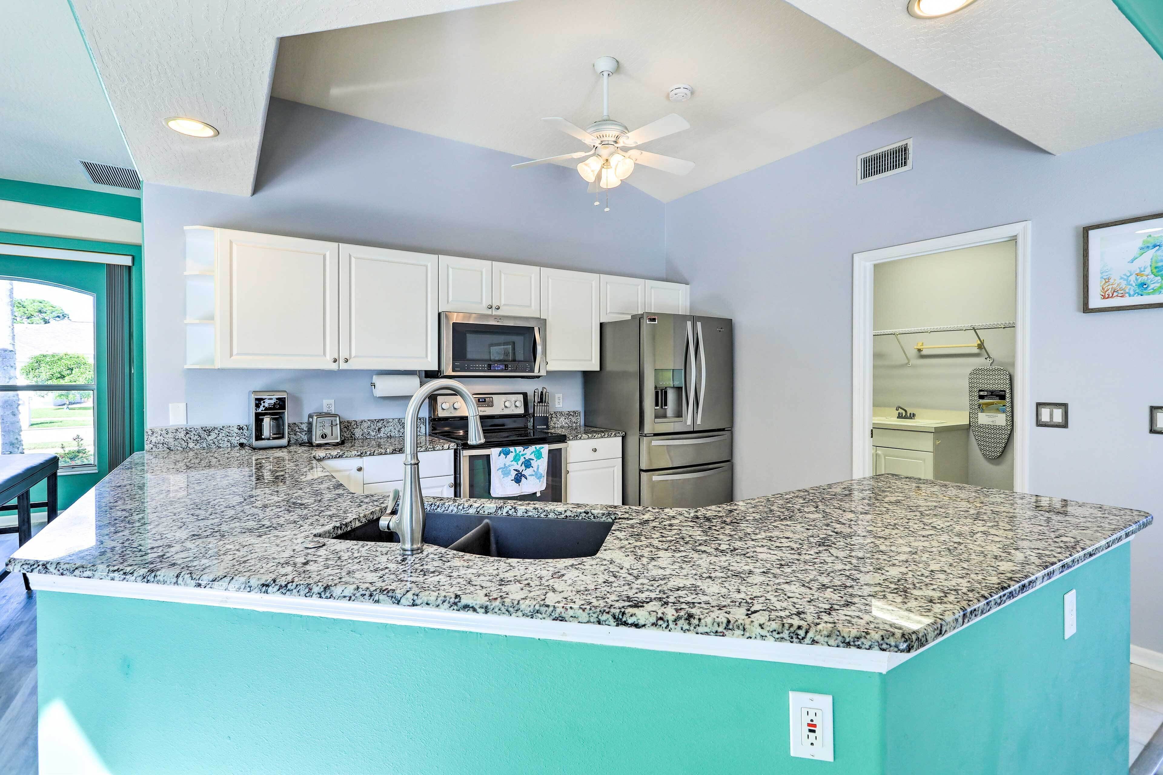 A modern kitchen with white cabinets, stainless steel appliances, and a granite countertop.