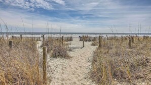 A sandy beach path with wooden posts and dry grass.